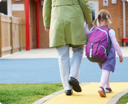 Child holding hands with parent walking into school